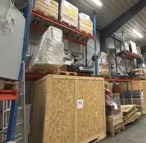 Malmö Flyttjänsts lager: staplade pallar, trälådor och hyllor.