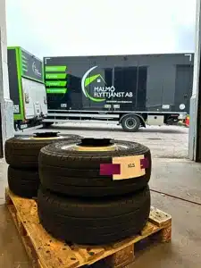 Tre staplade däck på en pall i en lagerlokal / flytt magasinering Malmö, med en lastbil i rörelse i bakgrunden.